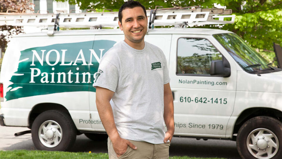 Nolan painting employee standing in front of Nolan painting van